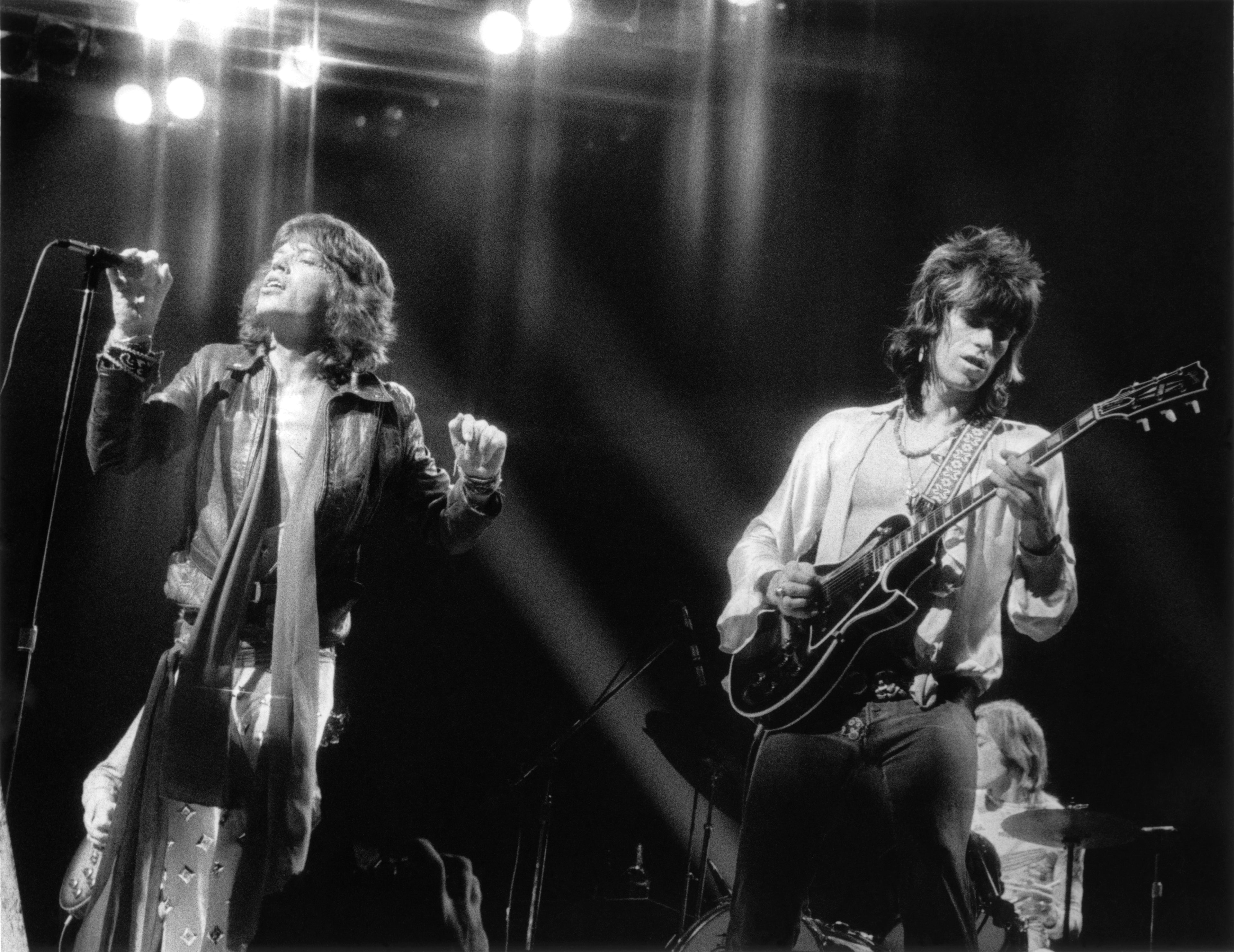 A black and white photo of The Rolling Stones performing on stage.